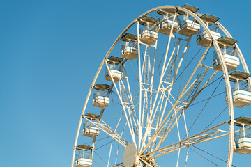 Large Ferris wheel stands against a bright blue sky, showcasing its white structure and gondolas.