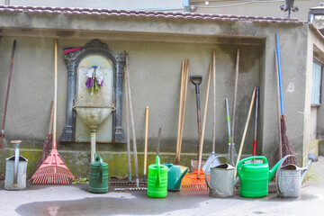 Garden tool shed interior displaying organized collection of watering cans and maintenance equipment