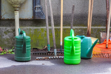 Fototapeta premium Garden storage corner with collection of watering cans and tools hanging in organized outdoor workspace