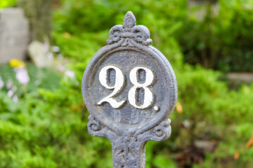 Ornate cemetery grave marker displaying number 98 with decorative metalwork and vintage styling in...