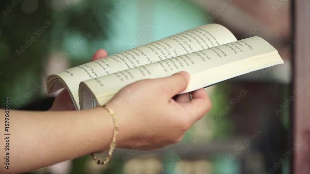 Poster close-up of a person holding and reading a book, with pages open. a calm and thoughtful moment in a 