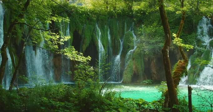 Scenic view of lush waterfalls cascading into a turquoise lake in Plitvice Lakes National Park Croatia