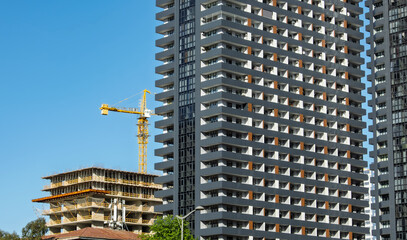 High-rise building and tower crane. Cityscape photograph capturing a modern building next to an under-construction structure with tower crane. idea of The architecture and ongoing development.