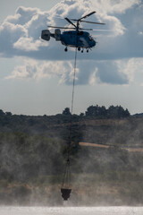 Helicopter performs water drop to combat forest fire in rural area during summer afternoon