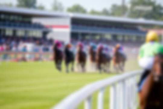 blurry racetrack, showing horses racing on a track with riders on them, blurry wallpaper.