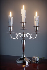 Elegant Silver Candle Holder with Three Lit Candles and a Single White Rose in Soft Ambient Light