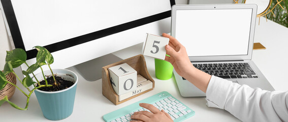 Woman with cube calendar and computers at workplace in office