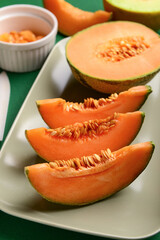 Plate with tasty ripe melon on green background