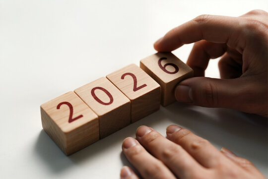 Hands adjusting wooden blocks to display the year 2026