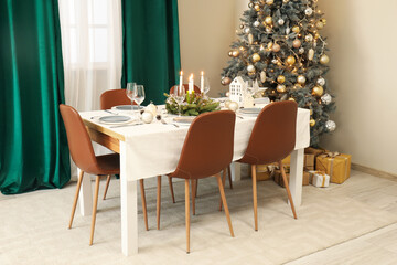 Festive table setting with burning candles and Christmas decorations in elegant dining room
