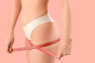 Beautiful young woman in underwear with measuring tape on pink background. Concept of cellulite