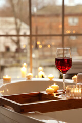 Stand with glass of wine and burning candles in bathroom, closeup