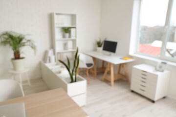 Blurred view of office with table, shelf units and plants