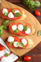 Tasty sandwiches with mozzarella cheese, tomatoes and basil on wooden table, flat lay