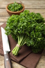 Fresh parsley and knife on wooden table, closeup