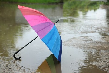 Colorful umbrella on wet asphalt under heavy rain. Space for text
