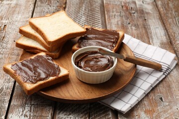Tasty chocolate butter, slices of bread and knife on wooden table, closeup