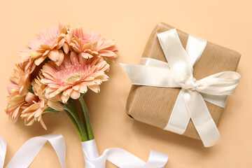 Gift box with gerbera flowers on beige background