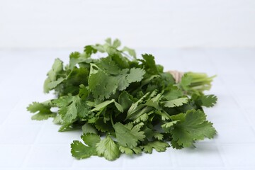 Fresh aromatic cilantro on white tiled table, closeup