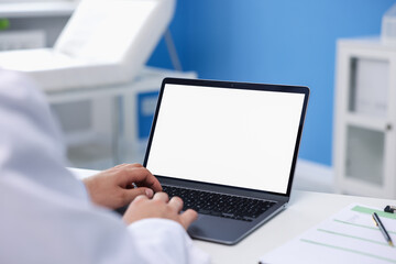 Doctor using laptop in clinic, closeup. Online medical consultation