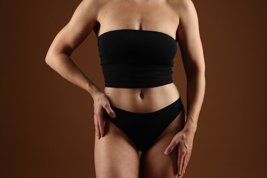Fit woman with perfect body on brown background, closeup