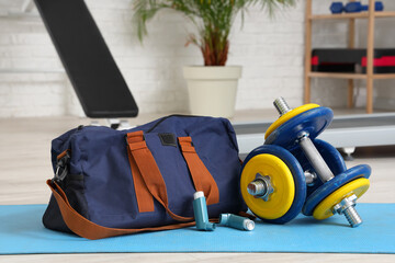 Asthma inhalers with sports bag and dumbbells in gym