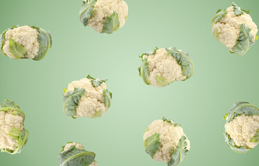 Fresh raw cauliflowers falling on green gradient background