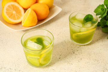 Glasses of tasty lemonade with mint and lemons on white background