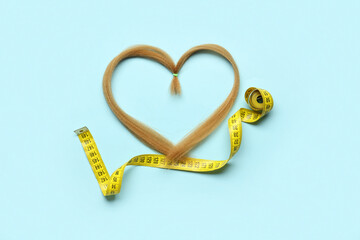 Heart made of red hair strand for donation and measuring tape on blue background