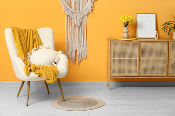 Beautiful interior of living room with white armchair, cushion and chest of drawers