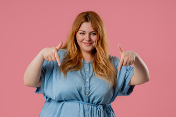 Plus size blogger woman pointing down advertising pink area. Click to subscribe
