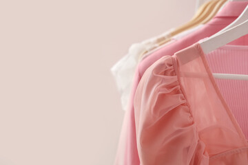 Rack with hanging clothes near pink wall