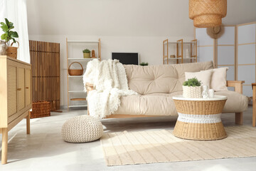 Obraz premium Wicker table and comfortable sofa in interior of stylish living room