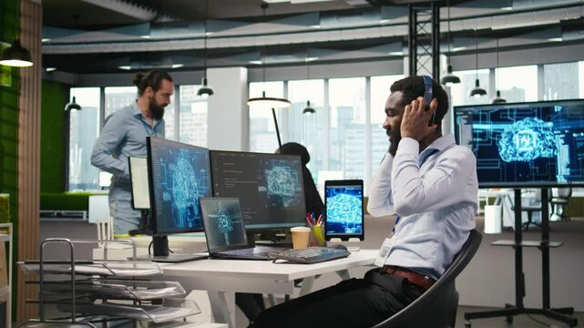 Programmer in office relies on AI machine learning to automate repetitive tasks, looking at devices. IT expert uses neural networks artificial intelligence to speed up feature implementation, camera A