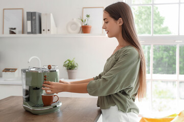 Beautiful young happy woman making coffee with machine at kitchen in office