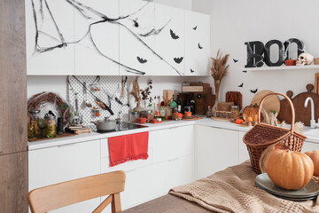 Interior of light kitchen decorated for Halloween with white counters and shelf