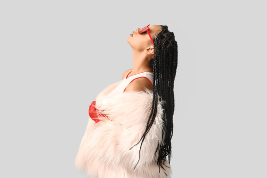 Stylish African-American woman with braids on light background