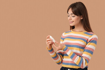 Young girl with eye drops on beige background