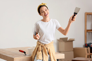 Young woman with putty knives smiling in room
