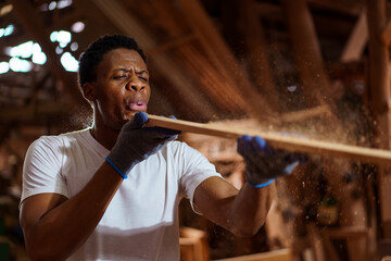 Professional African male carpenter is working professionally in sawmill - workshop.