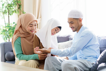 Obraz premium Happy Asian muslim family sits together in a cozy living room.