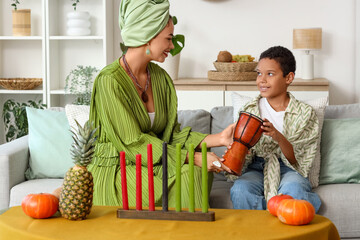 African-American mother with tam-tam drum and her son celebrating Kwanzaa at home