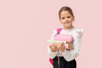 Cute little happy girl with backpack, pencil case and books on pink background