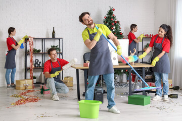 Team of janitors cleaning in office after New Year party