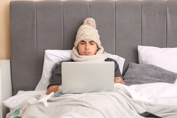 Ill young man using laptop in bedroom