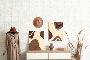 Chest of drawers, mannequin and paintings near white brick wall in room