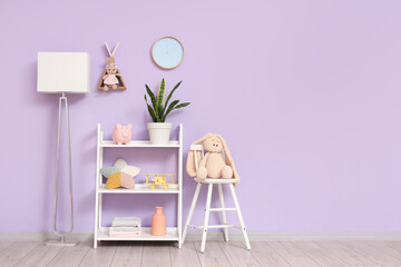 Interior of children's room with shelving unit, floor lamp and stool near lilac wall