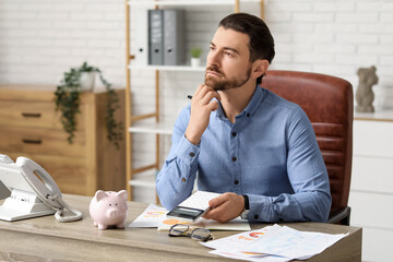 Businessman doing calculations at table in office
