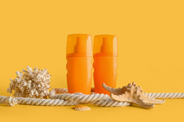Composition with bottles of sunscreen cream, rope, starfish, coral and seashells on yellow...