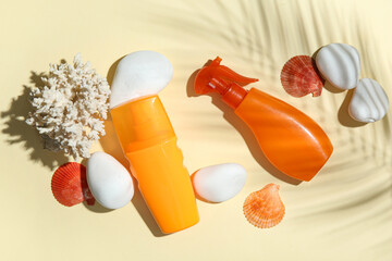 Seashells, coral, stones and bottles of sunscreen cream on beige background